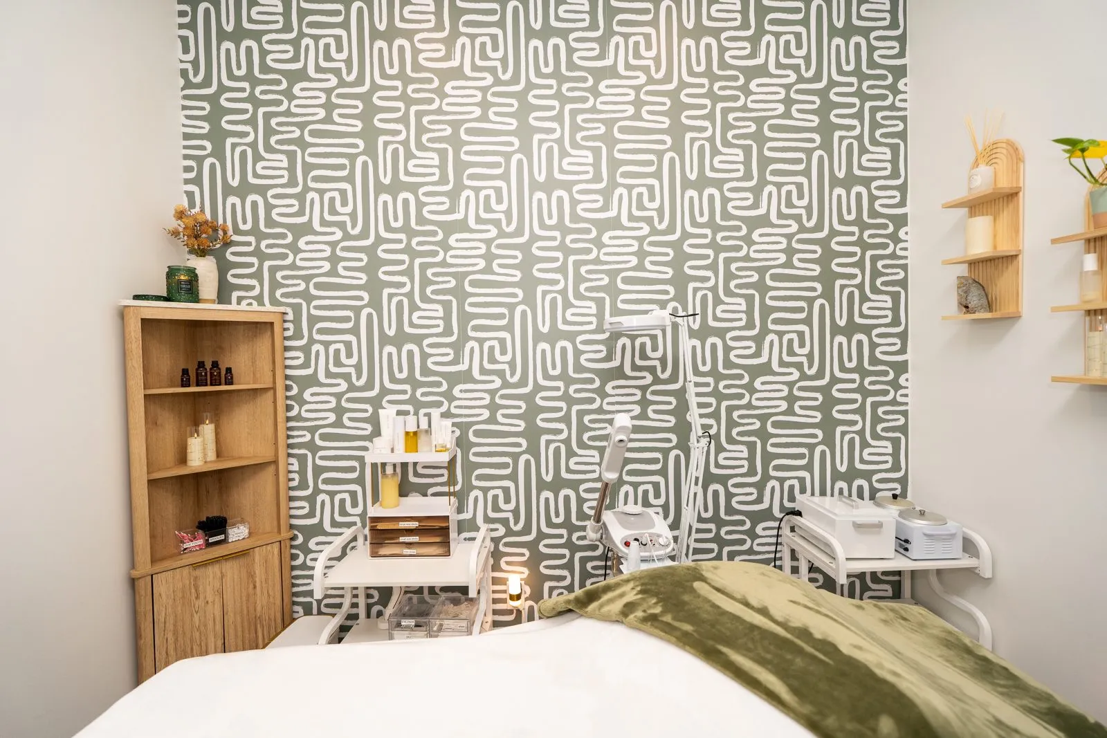 An esthetics room with a facial bed and skincare station