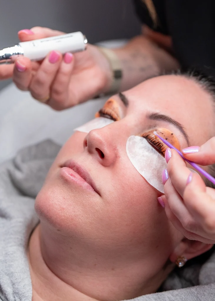 Close-up of Raw Glo med spa provider performing a lash lift treatment on a client with under-eye pads in place.